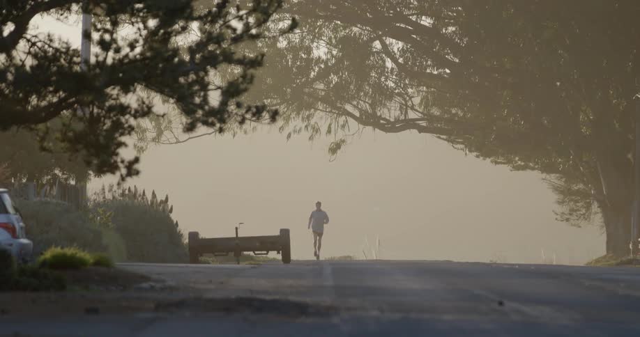 A man jogs down a road in the fog