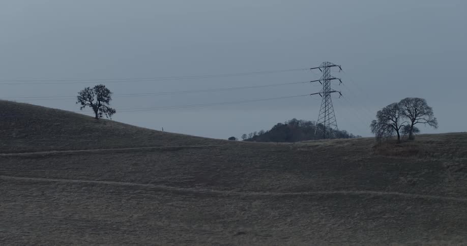 A distant person runs up a grassy hill