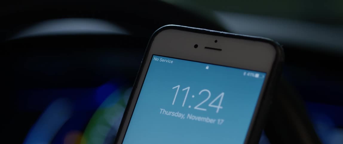 A smartphone is held up with a date and time displayed