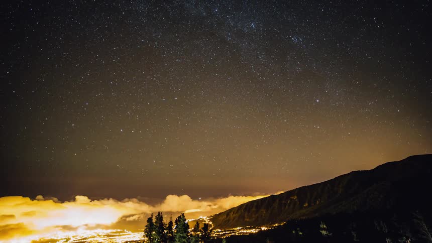 Clouds rolling onto a hill at night
