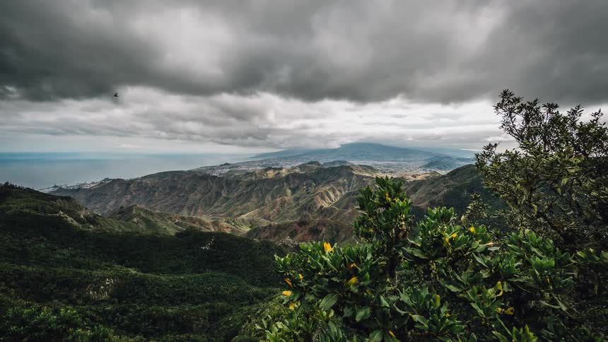 Storm clouds billow and hover over a mountain range