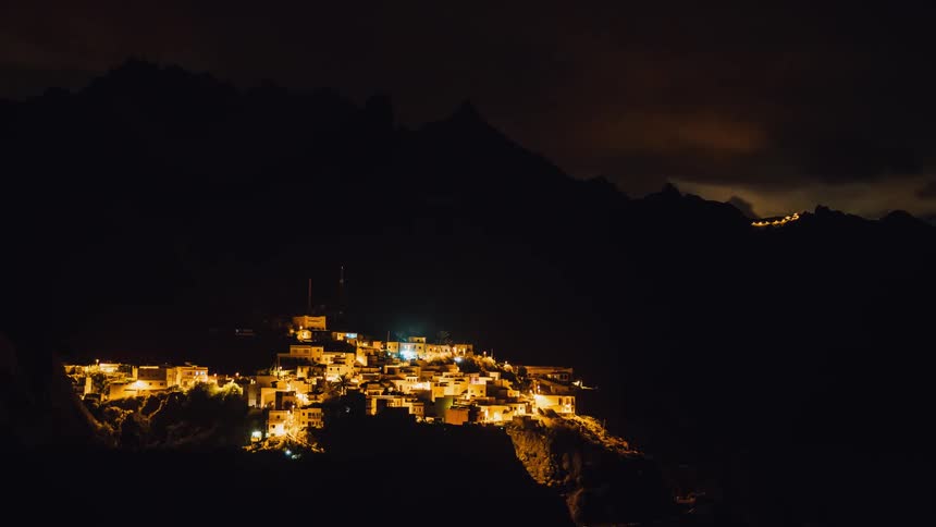 Lights illuminate a village near the mountains