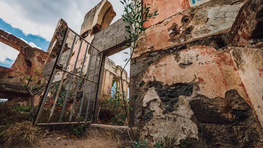 A steel door sits open along a tattered structure
