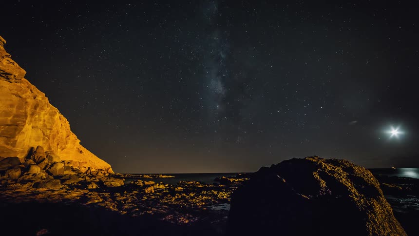 Water surrounds rocks under a night sky