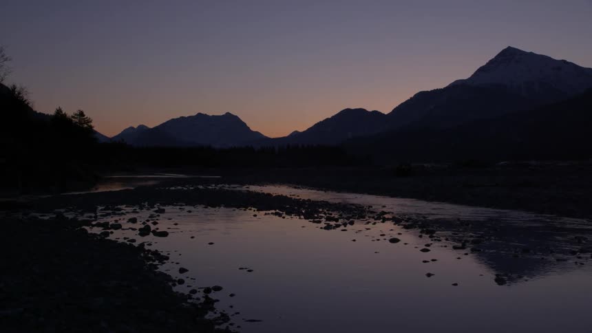 A calm stream is being filmed from the shore