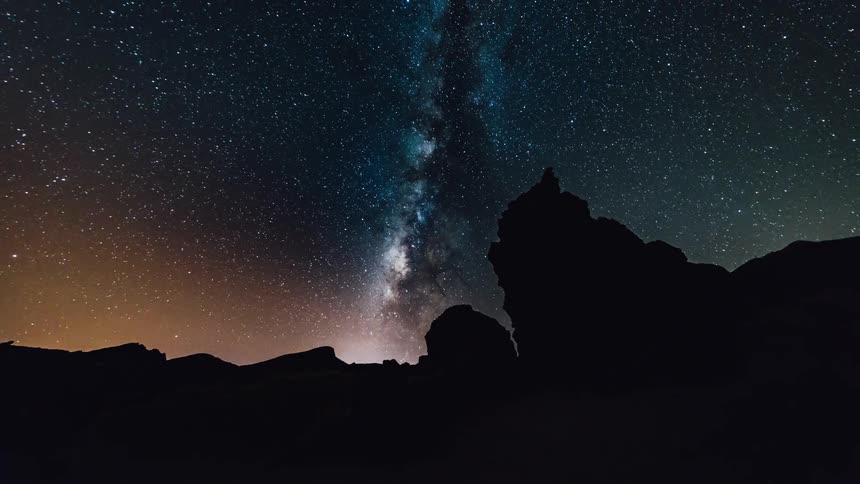 The sun is setting and stars appearing over a desert landscape