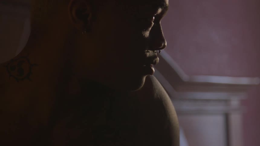A man without a shirt is sitting in contemplation