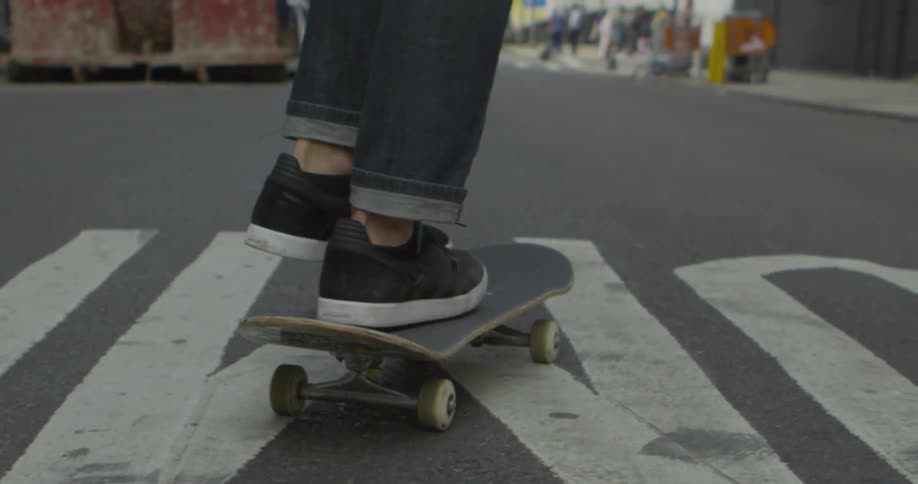 A skateboarder propels himself down a city street during the day