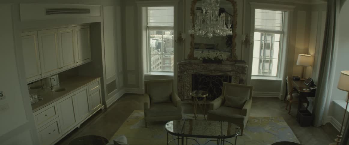 Two chairs sit underneath a chandelier