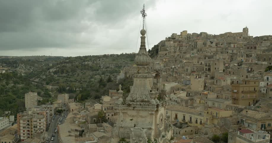 A church bell tower hovers above an old city on a cloudy day