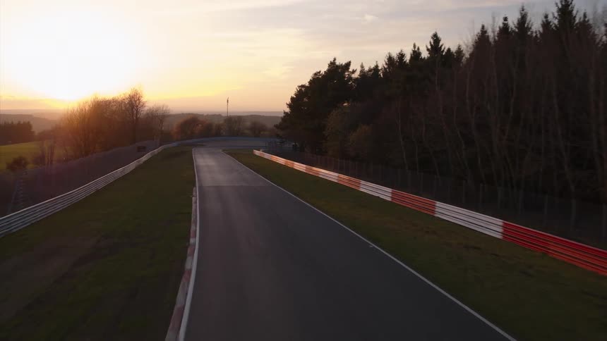 Barriers and trees line the side of a winding road driving track
