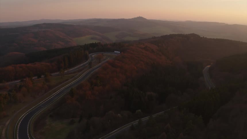 Trees line the side of a winding road driving track