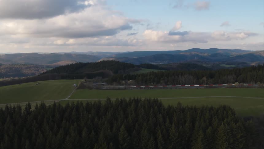 Large green field is surrounded by trees