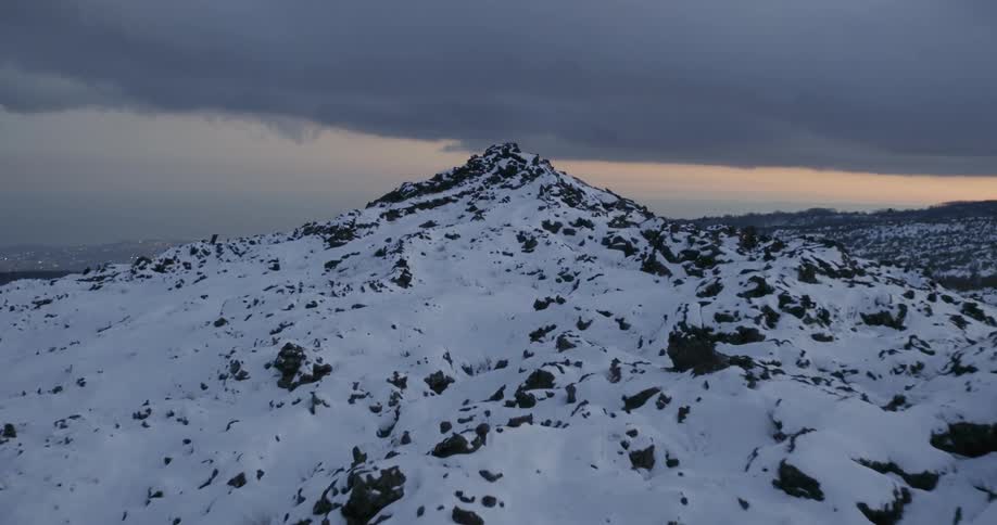 Storm clouds hover over a mountain range at dusk