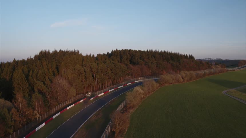 A road winds between a forest and fields in a rural area