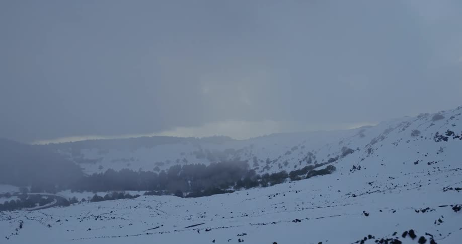 Clouds and fog hover over a snow-covered mountain range