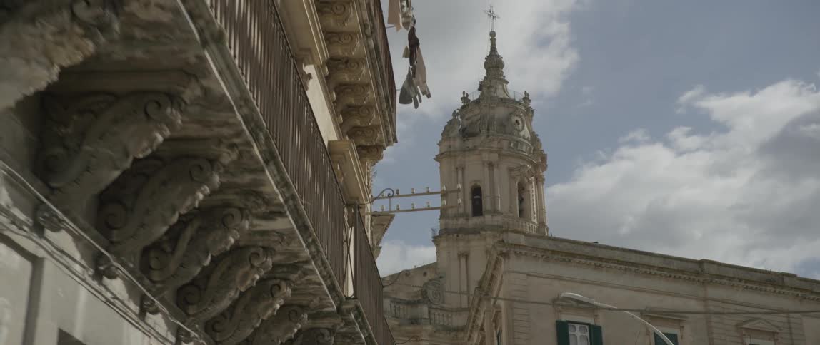 Ornate cement buildings sit under a cloudy sky