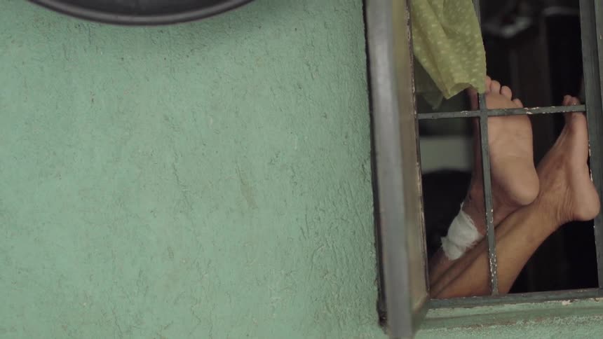 A person lays with their feet up against a window