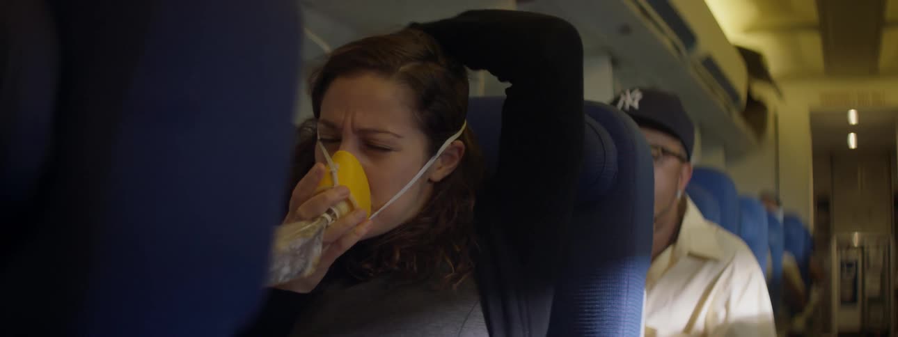 A female airline passenger struggles to put on an oxygen mask