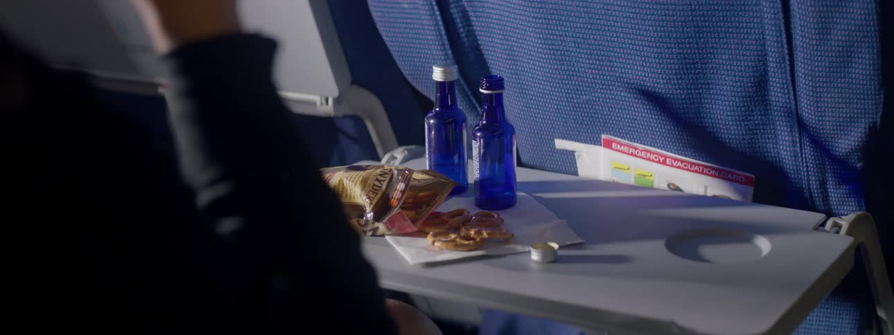 A woman on an airplane is taking a drink