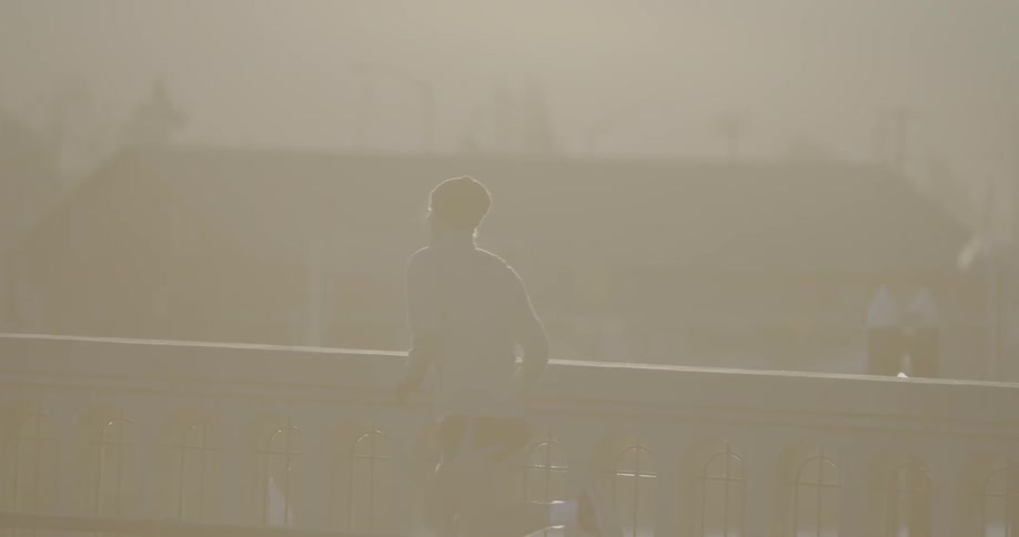 Man running down a foggy bridge