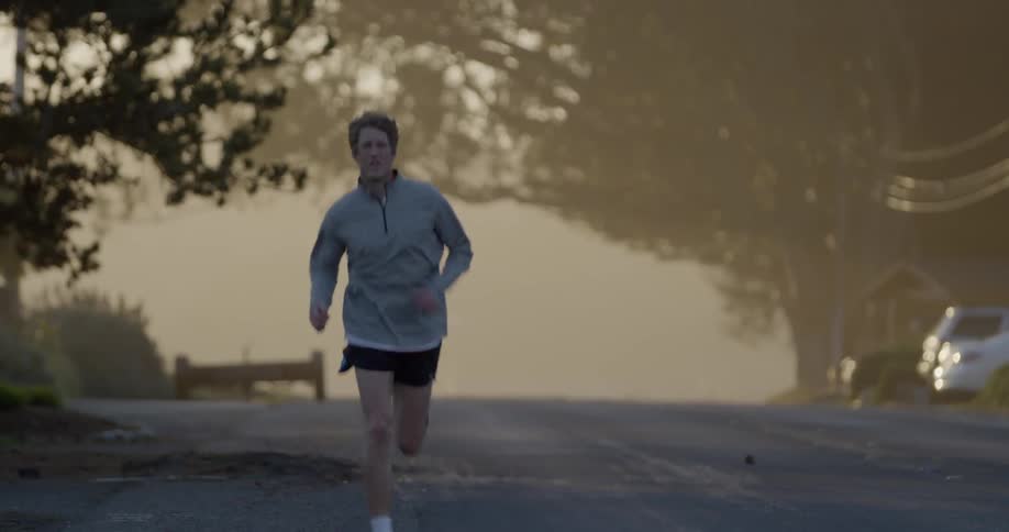 Man jogs down a road under some trees
