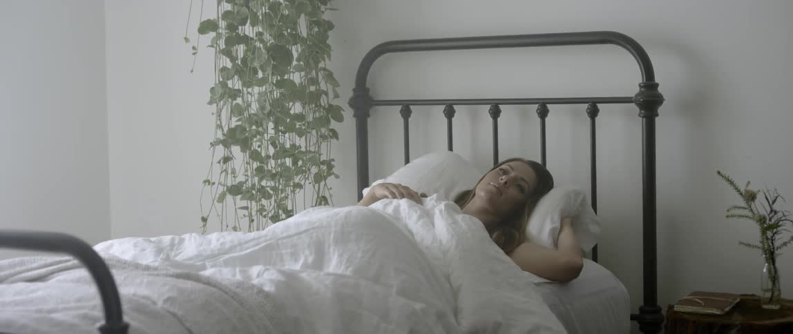A woman wakes while laying in bed