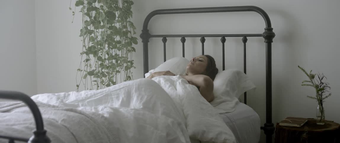 A woman lying in a bed sits up