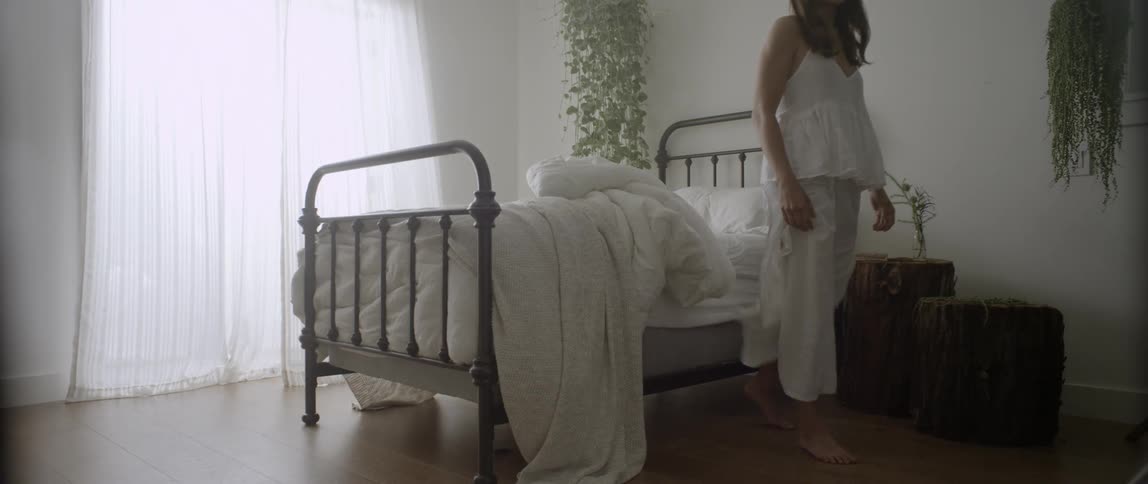 A woman stands up from bed