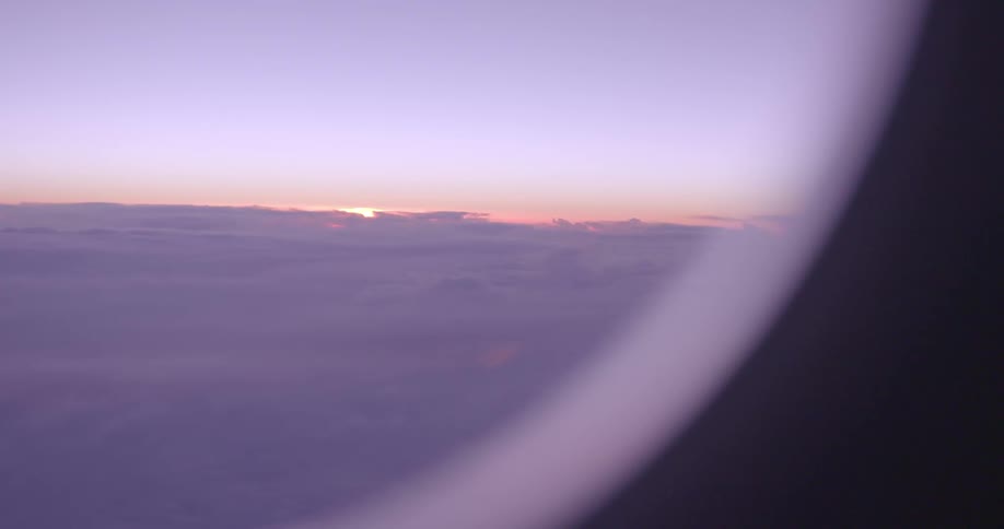 The sun can be seen through a window in a plane