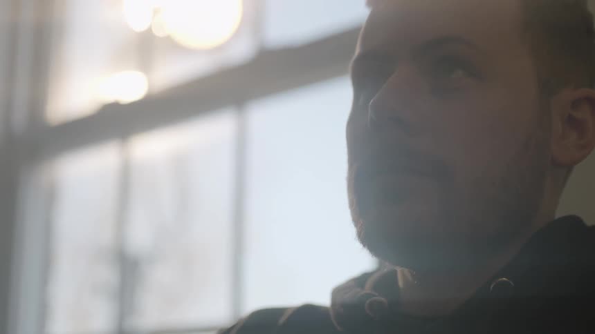 A man sitting near a window looks up