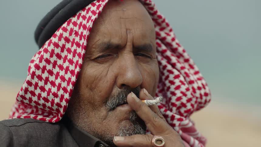 A man wearing a turban smokes a cigarette