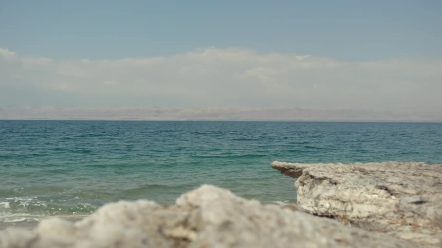 Waves crash into shore under a blue sky