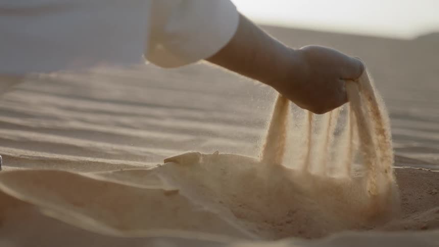 A man is picking up sand in the desert