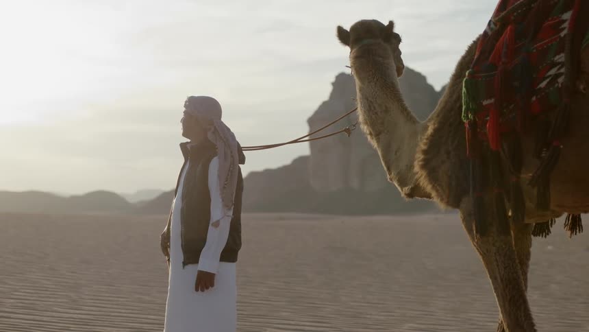 A man is holding the leash of his camel