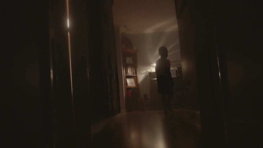 A young boy walks through his house at night