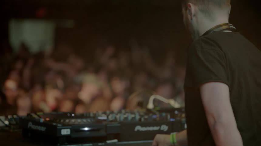 A dj jumps up and down in front of a crowd