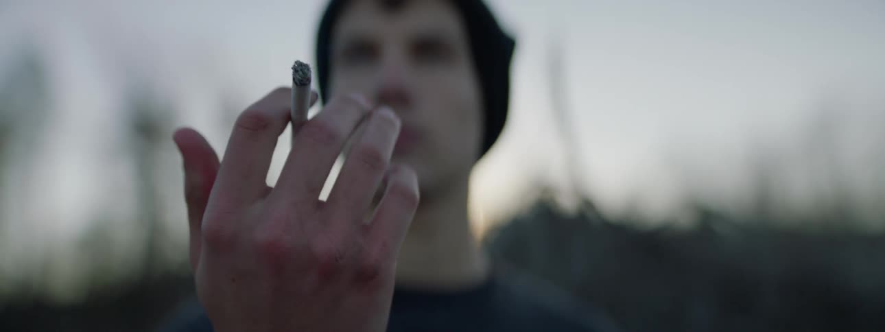 A man holds a lit cigarette