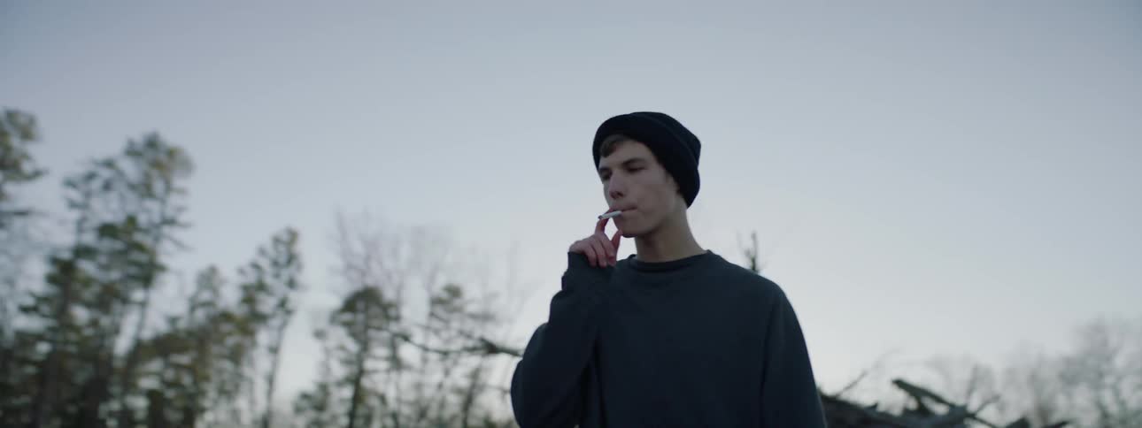 A man walks outside smoking a cigarette