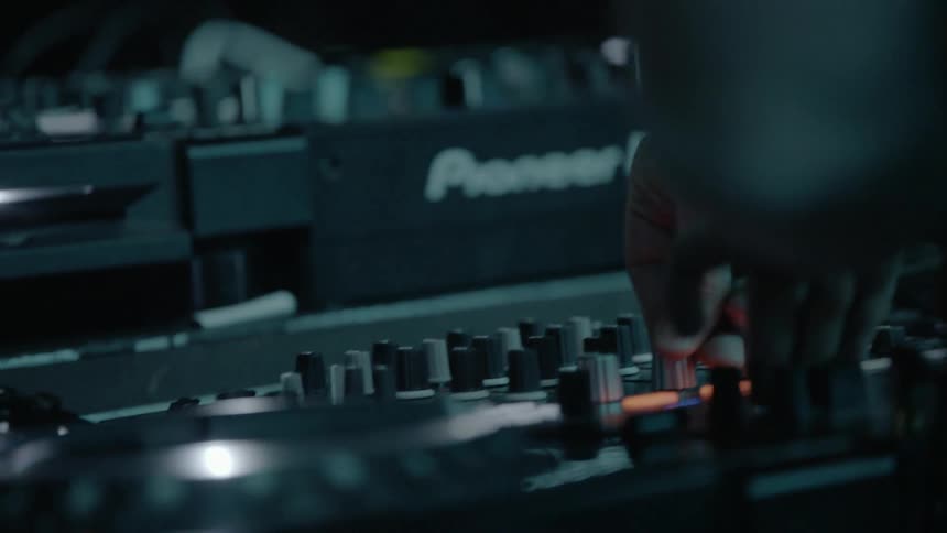 A dj adjusts and turns knobs on equipment