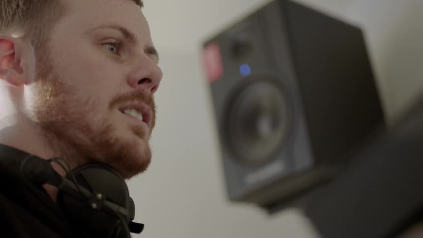 A musician nods his head to the music in a studio