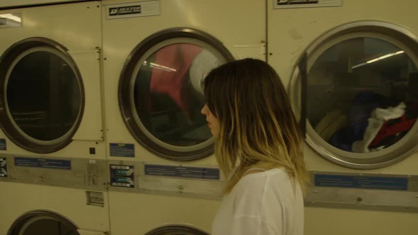 Woman walking in front of dryers at a laundromat