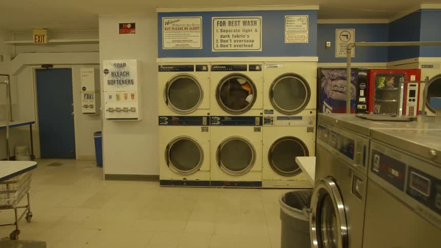 Clothes are spinning in a dryer at a laundromat