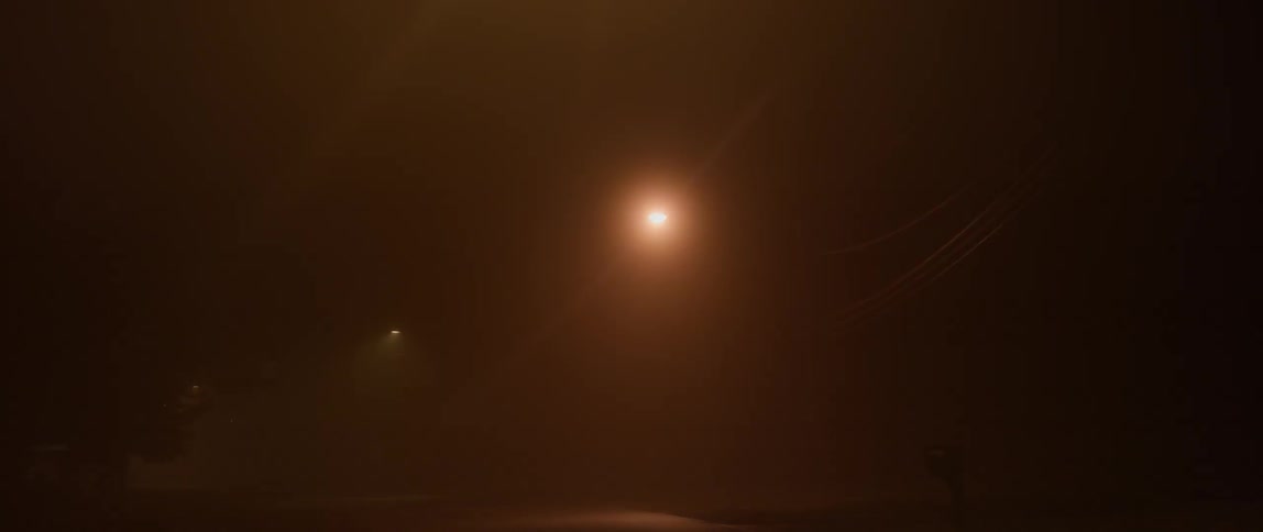 A car is driving down an extremely foggy road at night