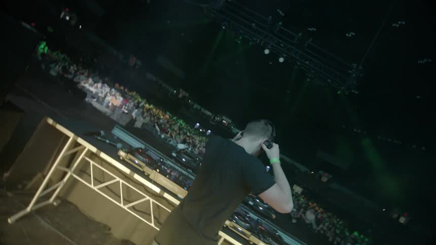 A dj puts on his headphones as he plays for a crowd