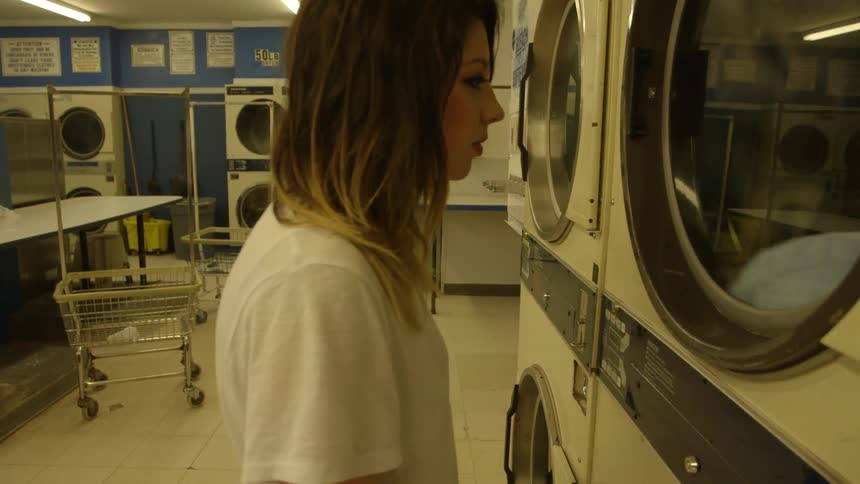 A woman washes clothes tumble dry in a laundromat
