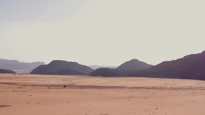 Person riding a camel through a desert