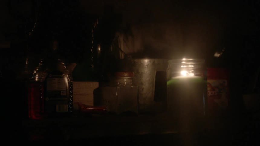 A candle is flickering on a shelf