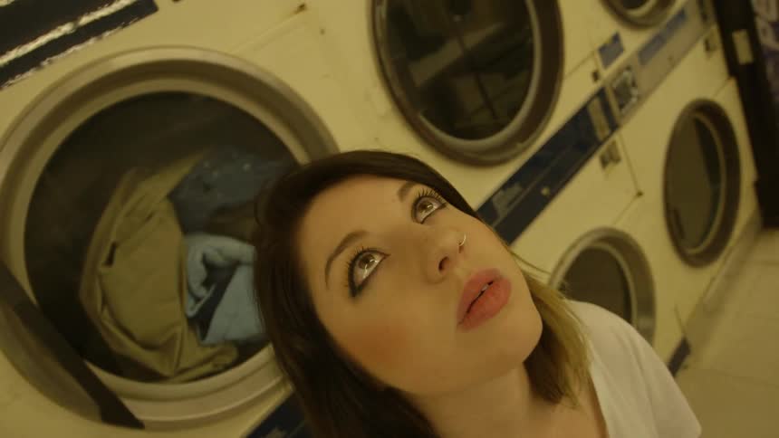 A woman looks up at the ceiling in a laundromat