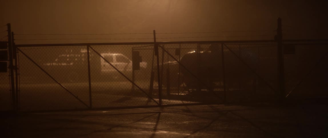 A fenced in parking lot at night
